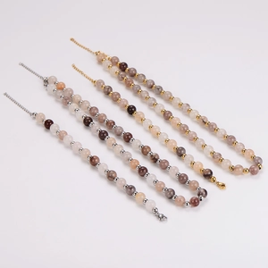 Natural agate beaded bracelets and necklaces with metallic spacers on beige background
