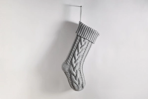 Close-up of grey cable-knit Christmas stocking with chunky texture and hanging loop