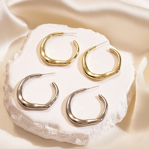 Irregular geometric hoop earrings in gold and silver finish on elegant marble display