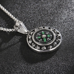 Detailed close-up of silver steel compass pendant with skull reliefs and metal chain