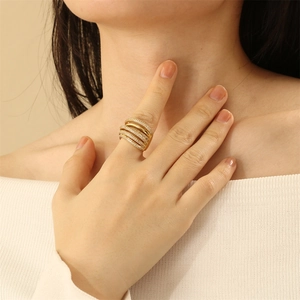 Detail of layered gold ring with zircon stones worn on model finger in soft lighting