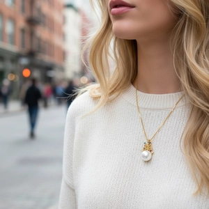 Close-up of golden crown necklace with large white freshwater pearl and colored stones