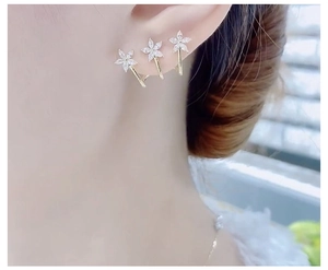 Side view of triple flower stud earrings with sparkling white zircons on a gold base