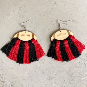 Detail view of American football wooden earrings with red and black braided thread tassels
