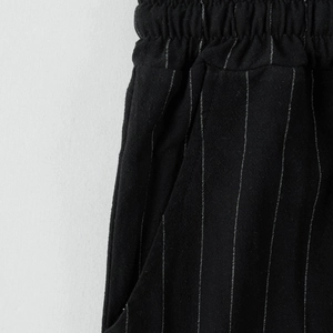 Dettaglio dei pantaloni in lino a righe nere con elastico in vita e tasca laterale