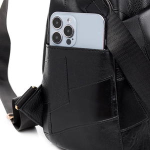 Detail of black leather backpack side pocket holding a smartphone for capacity display