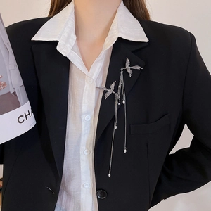 Close-up of silver phoenix brooch with cascading pearl tassels on a black blazer