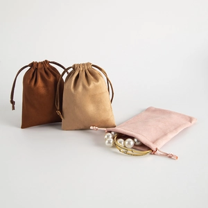 Detail of velvet drawstring jewelry pouches in brown, beige, and pink colors