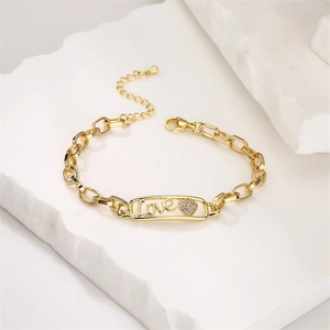 Detailed close-up of golden link bracelet with Love script and pave zircon heart charm