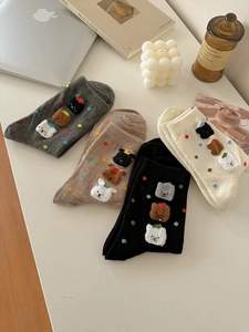 Dettaglio di calze in cotone in quattro colori con ricami di animali 3D e pois
