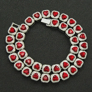 Macro shot of silver Cuban link chain with red heart crystals on black background