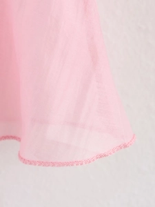 Détail de tissu rose translucide avec bords à volants et coutures de finition