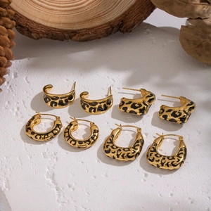 Detail of leopard print gold hoop earrings in semi-circle and U-shape on marble