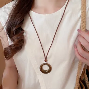 Bohemian style necklace with round amber resin pendant on long leather cord worn by model