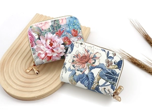 Detail view of floral print card holders with rose gold zippers on wood texture