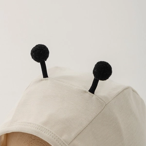 Close-up of baby knit hat with soft ribbed texture and cute black pompom antennae