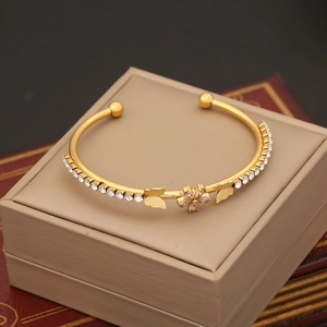 Golden flower and butterfly open bangle with sparkling cubic zirconia on a gift box