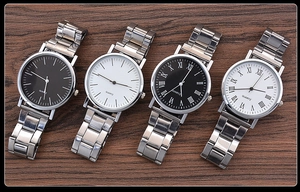 Close-up of quartz watches with silver metal straps on dark walnut wood background