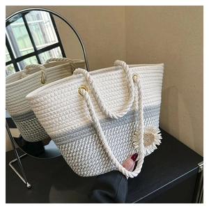 Detail of woven tote bag featuring two-tone texture and white floral accessory