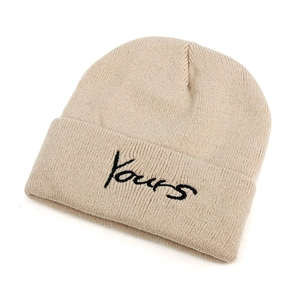 Beige wool knitted beanie with black Yours embroidery on a clean white background