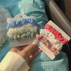 Close-up of floral and mesh scrunchie sets in blue and pink on white card displays