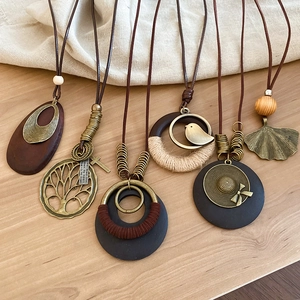Flat lay of bohemian wood and alloy pendant necklaces with leaf and tree motifs