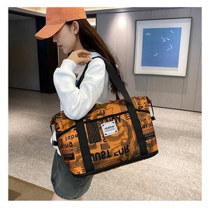 Detail of orange newspaper print travel bag with sturdy nylon straps and large capacity