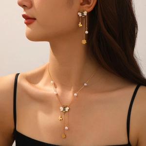 Close-up of gold-plated Y-shaped necklace and earrings set with bee and floral charms