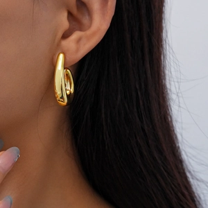 Close-up of minimalist gold circular hoop earring worn by a model against white background
