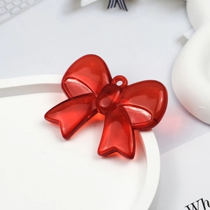 Close-up of a translucent red acrylic bow pendant with hanging hole on white platform
