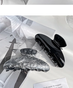 Detailed view of large black and marble acetate hair claws for elegant hairstyling