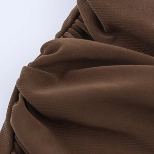 Close-up of deep brown pleated fabric showing detailed knitted texture and soft drape