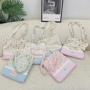 Detailed view of quilted cotton tote bags with floral prints and lace trim on plush background