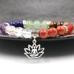 7 Chakra natural crystal bracelet with lotus pendant on black textured ceramic plate