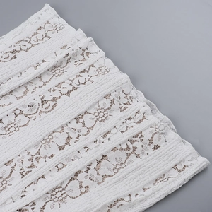 Close-up of intricate floral lace fabric and delicate cutout patterns on a white dress