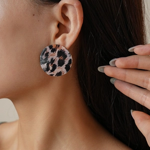 Gros plan sur boucle d'oreille ronde en acrylique léopard avec bordure dorée sur mannequin