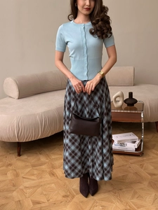 Cardigan in maglia azzurra con gonna lunga a quadri e borsa a mano in pelle