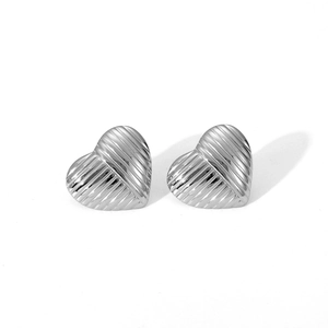 Macro shot of silver heart stud earrings with detailed horizontal textured grooves