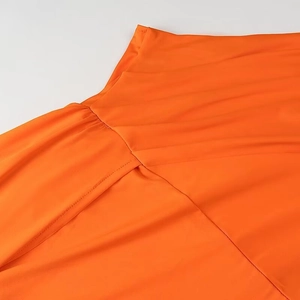 Détail rapproché de la couture à la taille et du tissu plissé de la robe longue orange