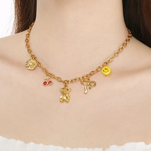 Close-up of golden necklace with flower, cherry, bear and smile pendants on model