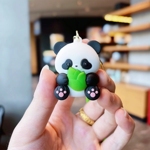 Close-up of a cute cartoon panda keychain with bamboo leaf and golden metal ring