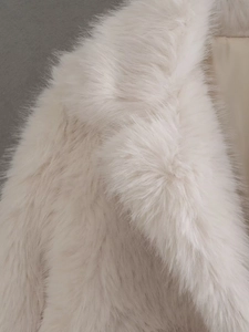 Dettaglio della pelliccia sintetica color crema e fodera in raso su un cappotto invernale