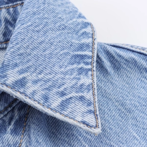 Detail of light blue denim shirt collar with contrast orange stitching and twill fabric