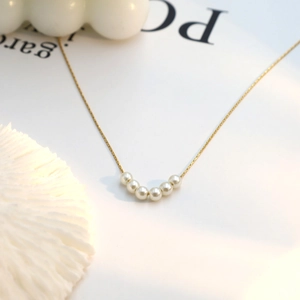 Detailed shot of six white pearls on a gold 18k titanium steel necklace chain