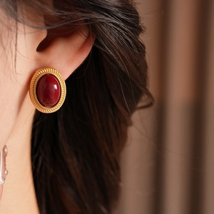 Close-up of vintage oval red gemstone earrings with gold-toned frame on a model ear