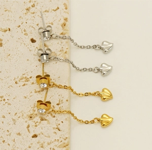 Close-up of polished gold and silver tassel heart earrings with sparkling cubic zirconia