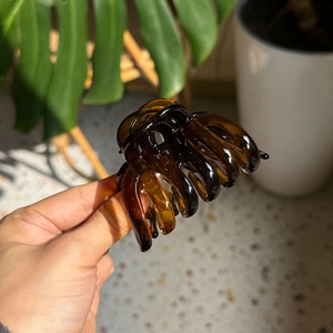 Detailed view of an amber pumpkin-shaped hair claw clip with a glossy translucent finish