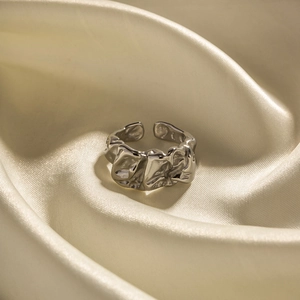 Adjustable silver stainless steel ring with irregular lava texture on silk fabric