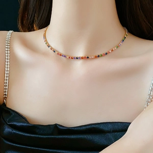 Close-up of gold-plated necklace with colorful round zircon stones on a female model