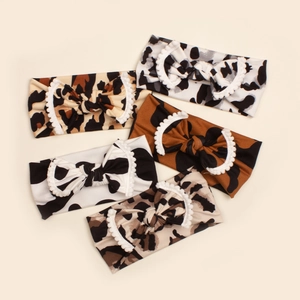 Set of five soft leopard and cow print baby headbands with white fluffy ball bows